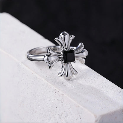 Gothic cross ring close-up, silver cross ring with black square stone on a white stone ledge
