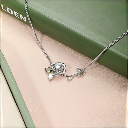 Vintage 3D rose pendant necklace close-up, silver rose pendant with a clear crystal centre and olive green crystal leaf, on a curb chain