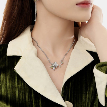 Model wearing a silver-tone three-dimensional rose necklace with green leaf details.