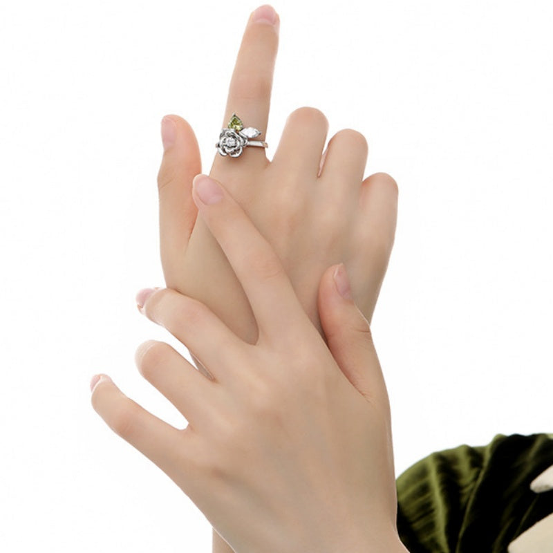 Model wearing a silver-tone sculpted rose ring with a green leaf detail.