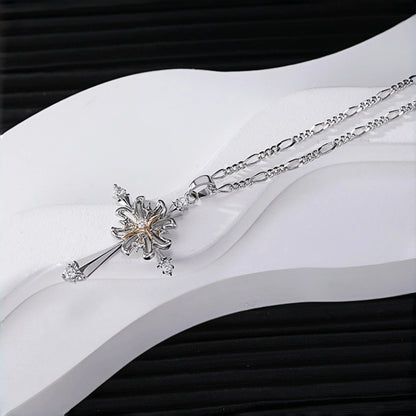 Vintage gothic cross pendant necklace close-up, silver cross with rose gold flower centre and clear crystal accents, on a figaro chain, resting on a white curved display