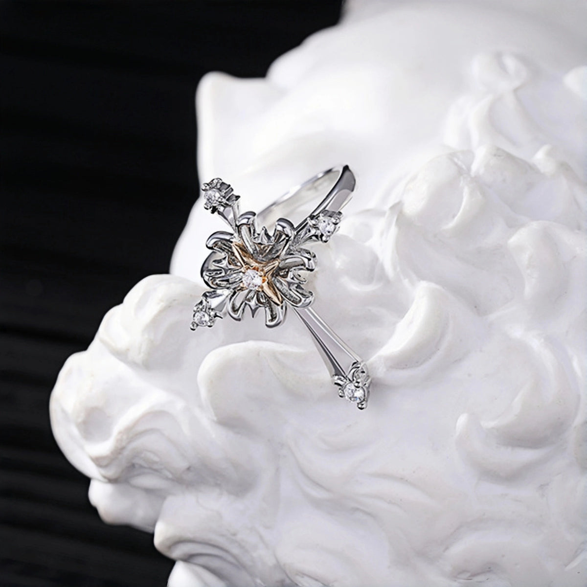 Vintage gothic cross ring close-up, silver cross ring with rose gold flower centre and clear crystal accents, on a white textured surface