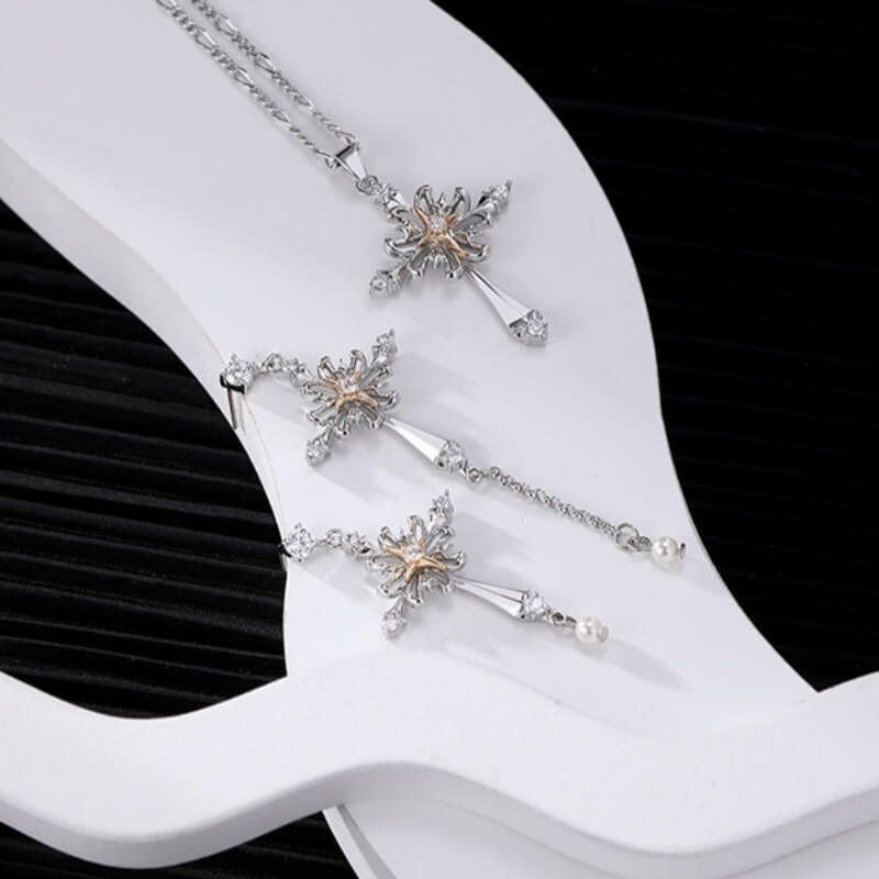 Ornate silver-tone cross necklace and mismatched drop earrings with gold-tone centres displayed together.