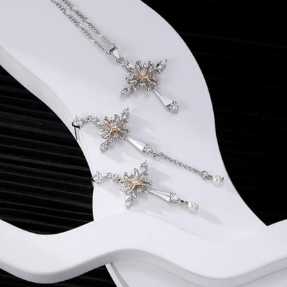 Ornate silver-tone cross necklace and mismatched drop earrings with gold-tone centres displayed together.