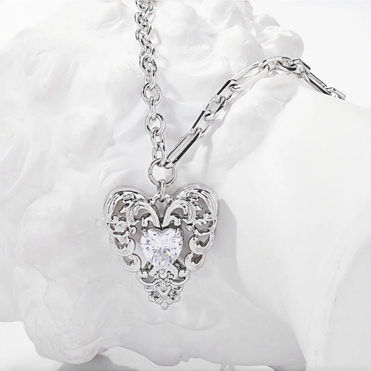 Vintage lace heart pendant necklace close-up, silver filigree heart pendant with clear heart-shaped crystal on a double chain