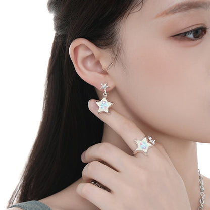 Close-up of a model wearing a white star drop earring and matching star ring in silver-tone settings.