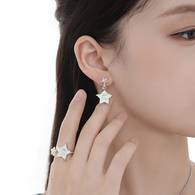 Side view of a model wearing a white star drop earring and matching star ring.
