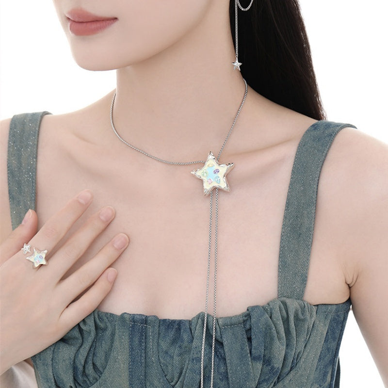 Model wearing a white star pendant necklace with long chain drops and a matching star ring.