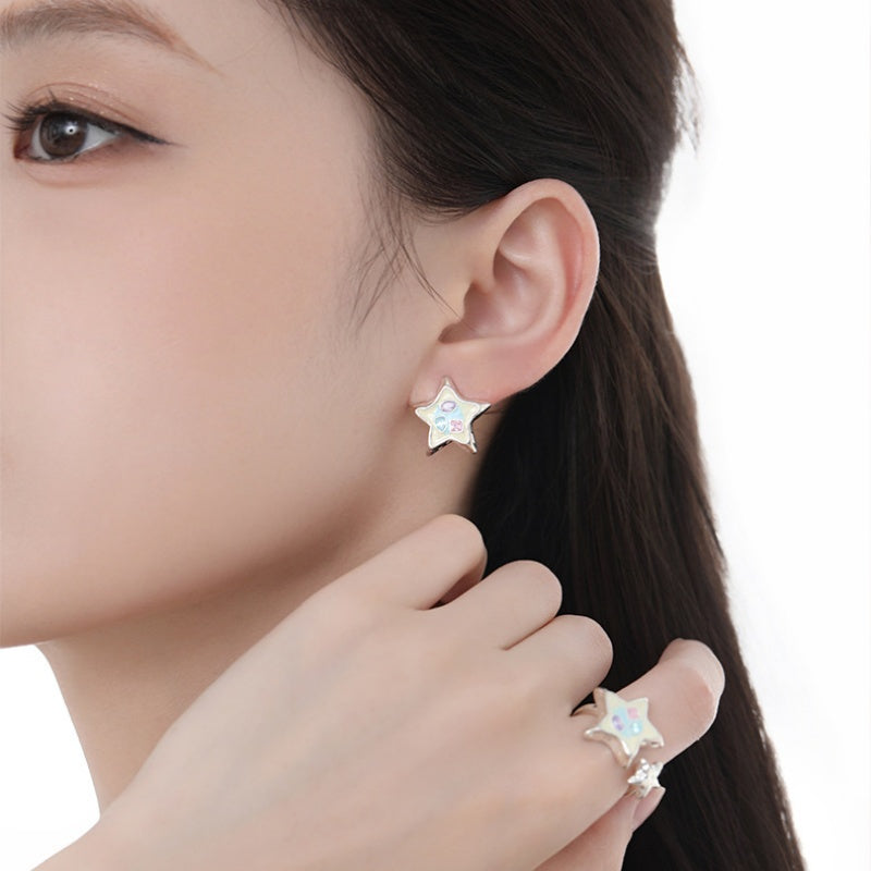 Close-up of a model wearing a white star stud earring and matching star ring.