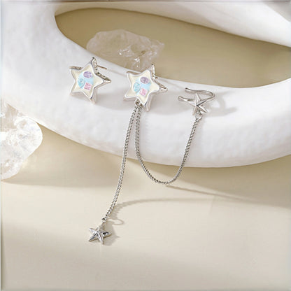 Colourful star earrings close-up, asymmetric pair with one enamel star stud featuring pastel crystals and one plain star stud with a dangling star charm on a chain
