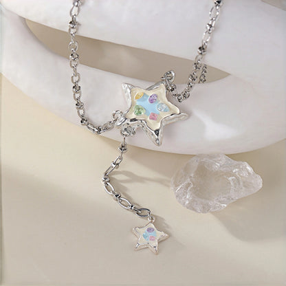 Enamel star lariat necklace close-up, silver enamel star pendant with pastel crystals on a rolo chain with a smaller star charm dangling below, beside a crystal rock