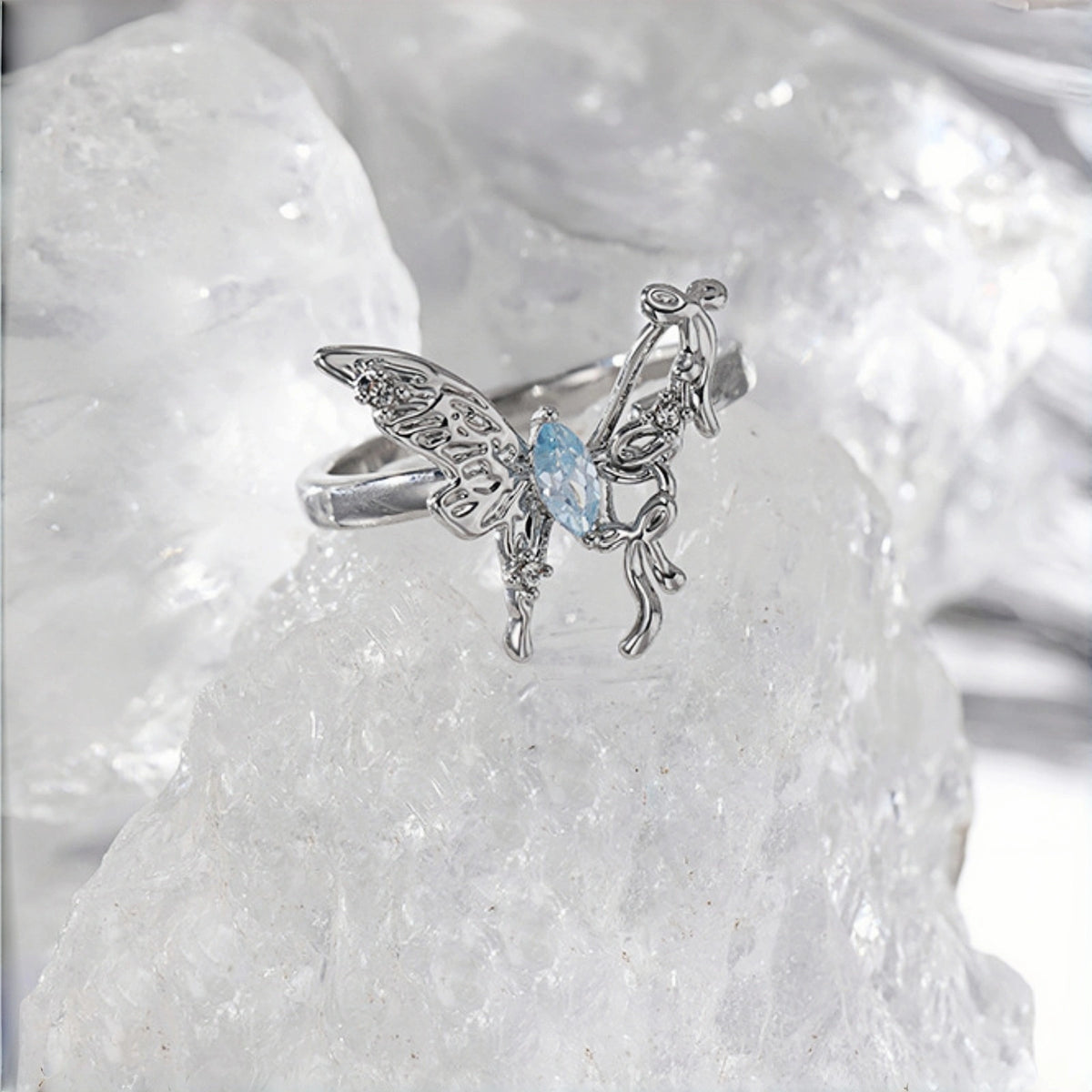 Fairy butterfly ring close-up, open silver filigree butterfly ring with a marquise blue crystal centre, on a crystal rock