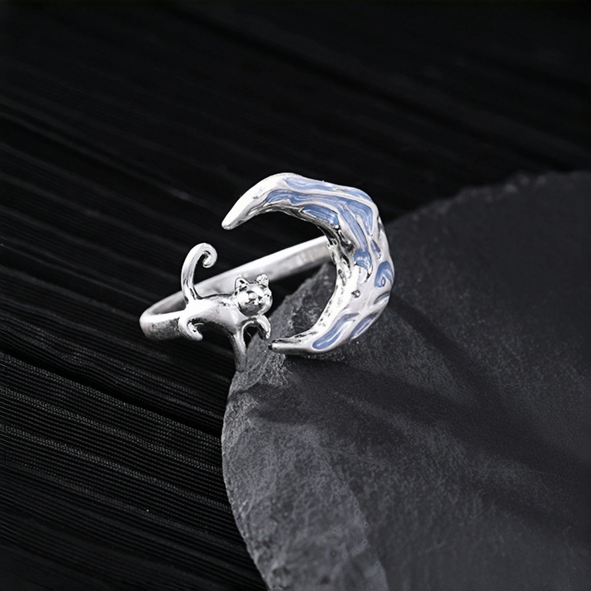 Moon and cat ring close-up, silver open ring with a crescent moon charm featuring blue enamel and a small cat detail