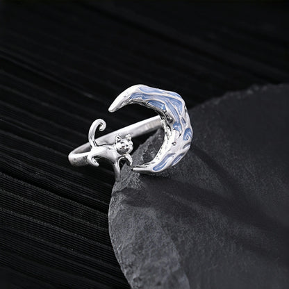 Moon and cat ring close-up, silver open ring with a crescent moon charm featuring blue enamel and a small cat detail