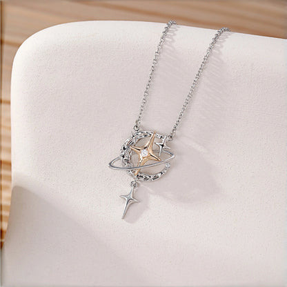 Y2K planet and star necklace close-up, silver orbit ring with gold star charm and dangling star pendant on cream fabric