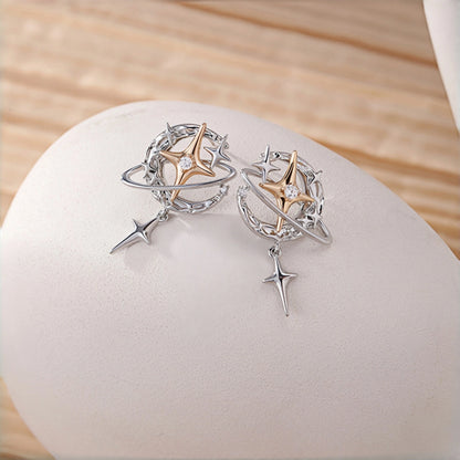 Y2K planet and star earrings close-up, pair of silver orbit hoop earrings with gold star charms and dangling star drops